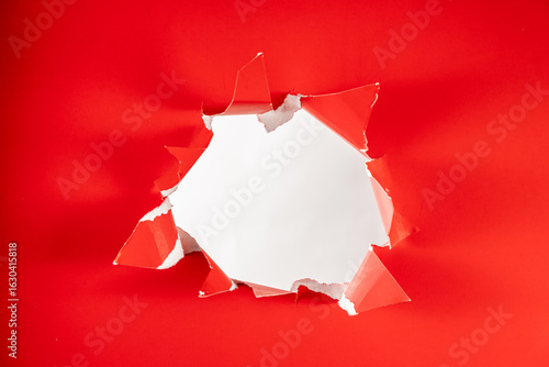 Photo of Solid red background ripped hole reviling white backdrop
