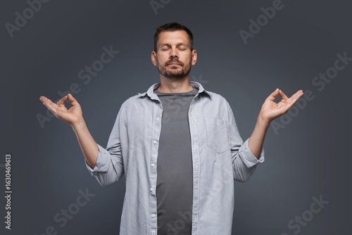 Panic attack. Man meditating to calm down on grey background