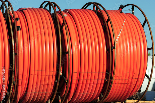 Εκτύπωση καμβά Large spools of orange conduit piping stored at a utility construction site, used for underground electrical, fiber optic, and telecommunications cable installation in infrastructure projects