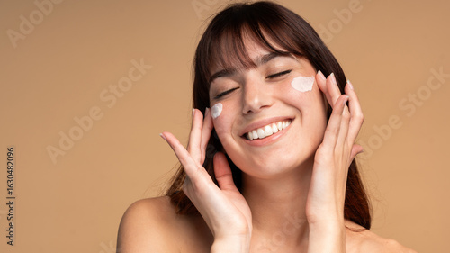 Beautiful young woman applying face luxury sunscreen or moisturizer cream for perfect hydrated healthy fresh skin care - Cosmetic dermatology product concept
