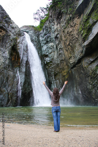 young happy woman traveler standing near waterfall, Dominican Republic 