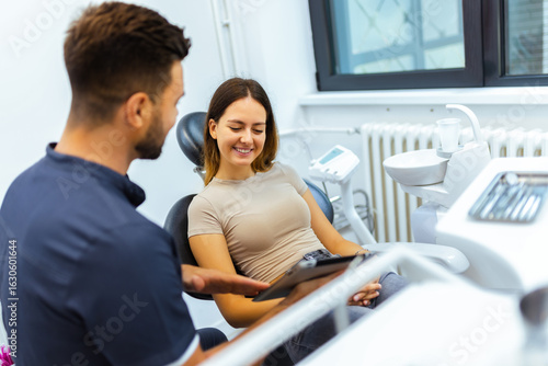 Male Dentist Showing Information on Tablet to Female Patient
