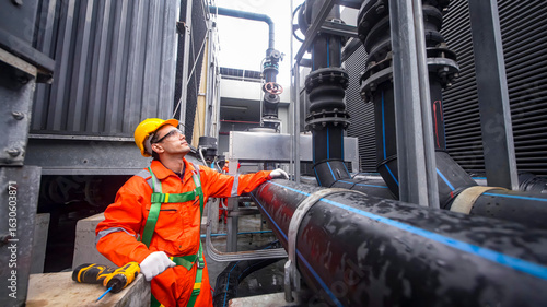 Worker inspects industrial piping system in a modern facility during the day