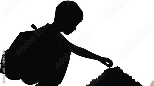 Silhouette of a child playing with sand on a beach with a backpack on