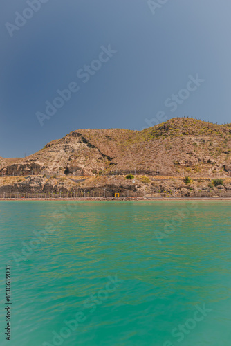 Blue sea with semi-desert mountains and blue sky in the background