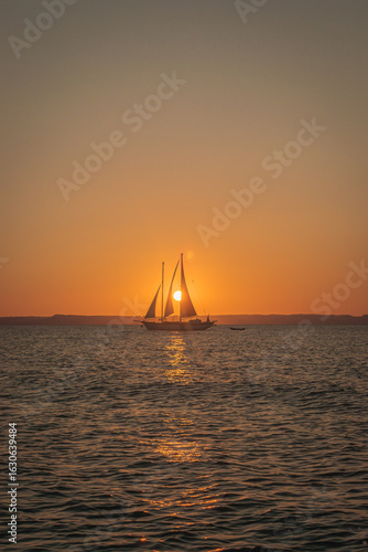 Sailboat at Sunset with Golden Light Reflected Across the Ocean