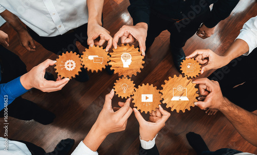Team members collaborate using wooden gears to symbolize ideas and technology, fostering communication and innovation in a modern business environment. Amity