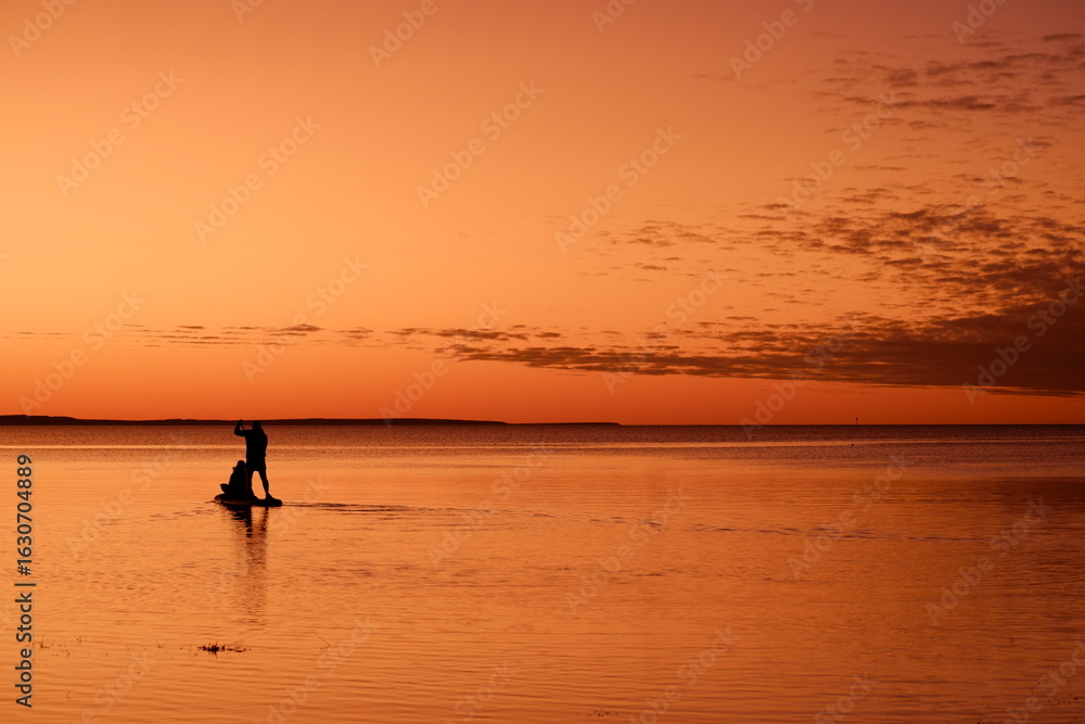 Paddleboarders on calm water at orange sunset
Paddleboarders on calm water at orange sunset