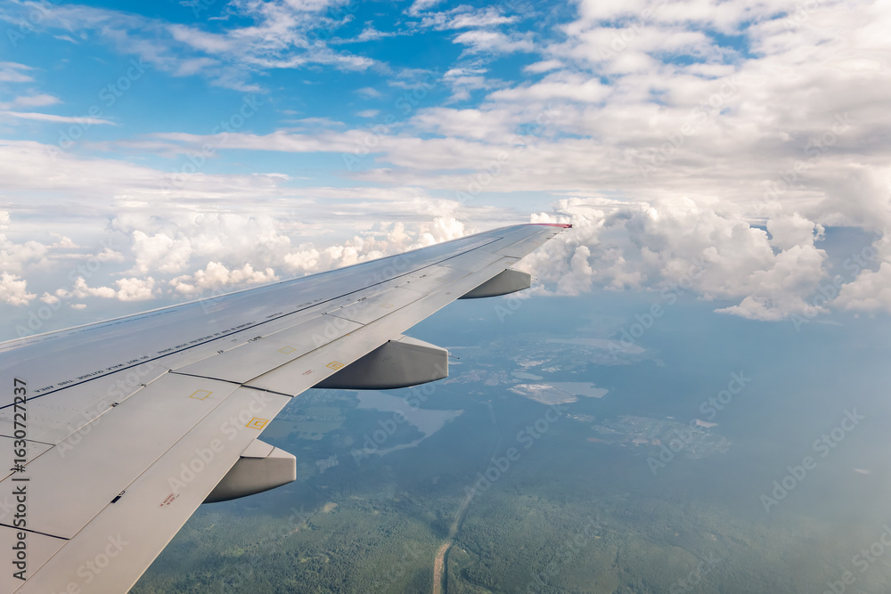 Obraz premium View from the airplane window at a beautiful cloudy sky and the airplane wing