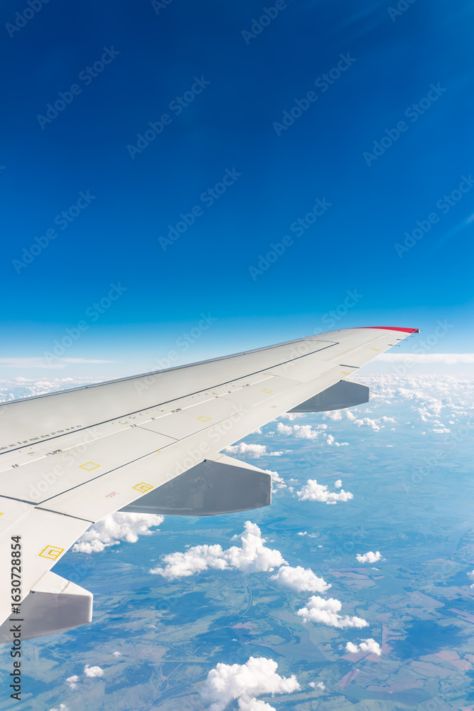Fototapeta premium View from the airplane window at a beautiful cloudy sky and the airplane wing