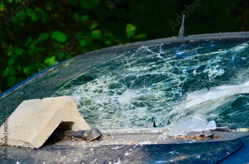 Close-up of a car after an accident with a shattered windshield. Glass fragments and visible damage to the vehicle's body emphasize the impact. A realistic depiction of a traffic accident, suitable fo