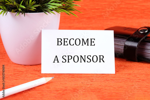 Photos BECOME A SPONSOR text written on a business card next to a business card holder,