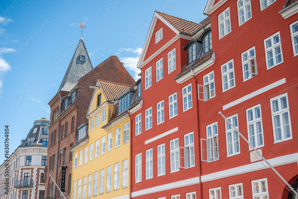 Fototapeta premium Les maisons colorées sur les rives du canal Nyhavn, au cœur de la ville de Copenhague au Danemark, avec des bateaux