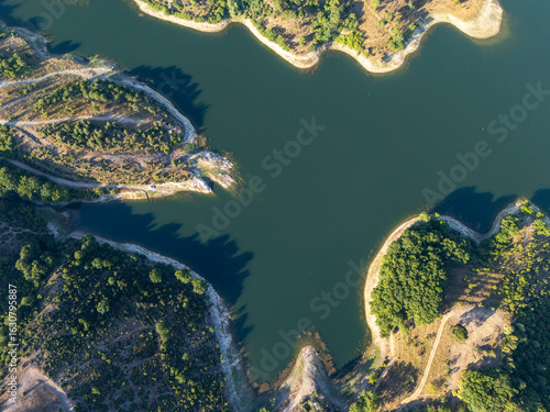 Top-down aerial view of Ömerli Dam showing curving shorelines, calm blue water, and dense forest areas, capturing the natural geometry, textures, and serene beauty of this large reservoir.

