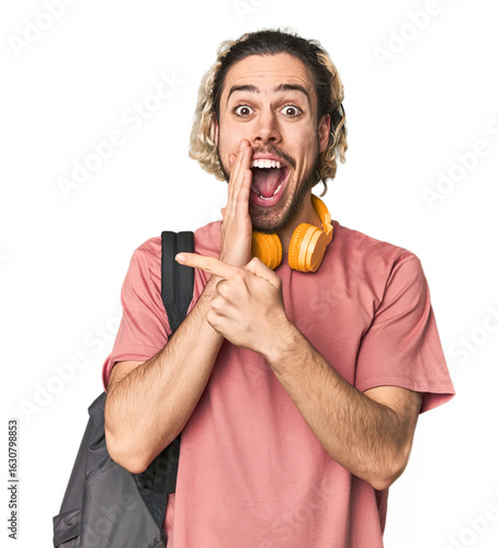 Fototapete Young student with backpack and headphones saying a gossip, pointing to side reporting something
