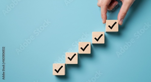 Checklist success concept with hand placing last checkmark on wooden cubes symbolizing completion and progress