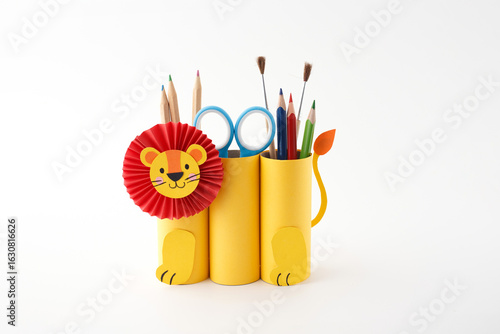 Yellow pencil holder shaped like lion with red paper mane, paws, and tail, filled with colorful stationery, ideal for kids products, school campaigns, DIY blogs, or craft brands