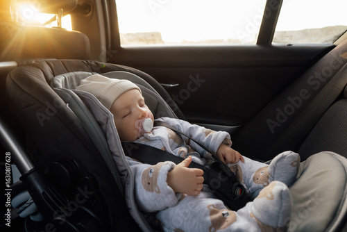 Baby sleeping in an infant car seat, safety travelling by car with little child. Little baby fastened with seat belt in safety car seat. Road trip lifestyle child care transportation rear-facing.
