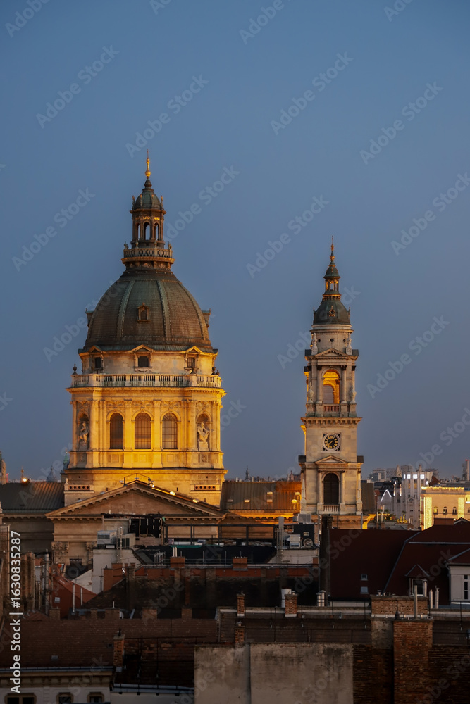 Fototapeta premium Close-up view at the illuminated dome and bell tower of St.Stephens Basilica surrounded by the roofs of old town.Budapest,Hungary 