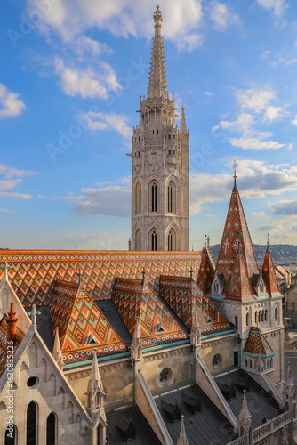 Photography The aerial view at the colorful roof and bell tower of Matthias Church against blue sky with clouds