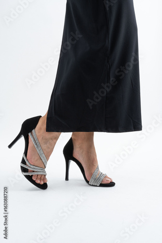 Elegantes sandalias de tacón alto con tiras de pedrería y falda negra