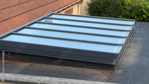 A large, modern skylight or roof window on a residential flat roof