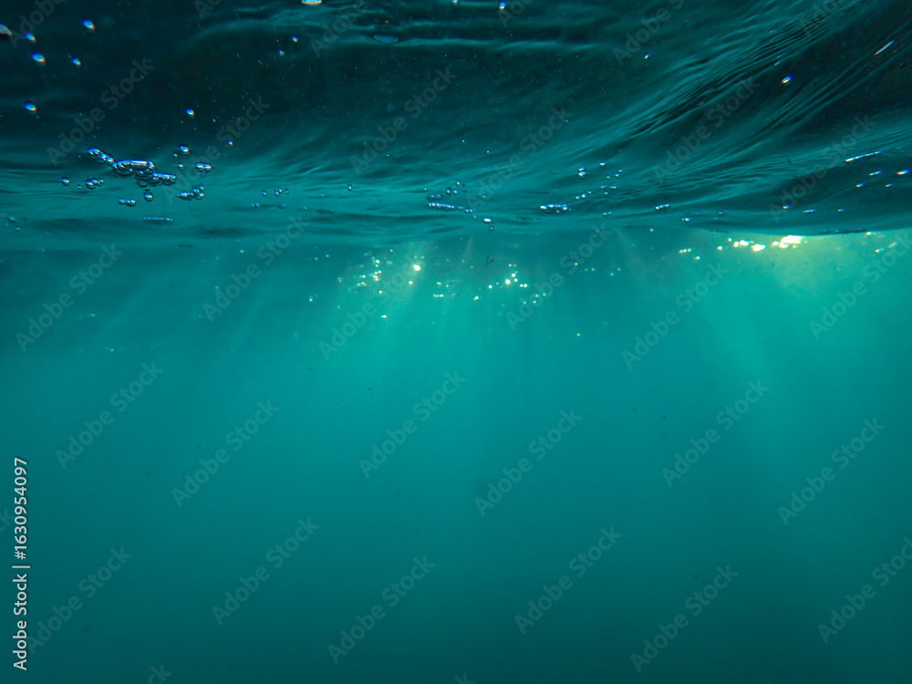 Obraz premium The sun shines through water, casting mottled light and shadow, intertwined with countless bubbles underwater, like a dance of light. Various aquatic, fish swimming in water in Mediterranean sea.