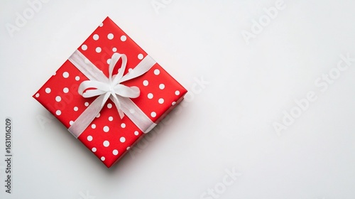 Festive red polka dot gift box with white ribbon on clean background