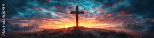 A wooden cross stands tall against a vibrant sunrise and dramatic clouds