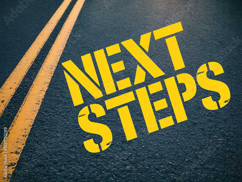 Yellow next steps text painted on asphalt road with double yellow lines
