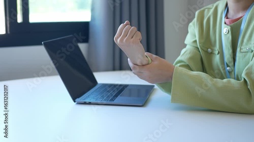 Young Asian woman feels numbness and severe pain in her wrist Caused by sitting and working for a long time Health care and office syndrome concept.