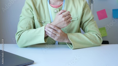 Young Asian woman feels numbness and severe pain in her wrist Caused by sitting and working for a long time Health care and office syndrome concept.