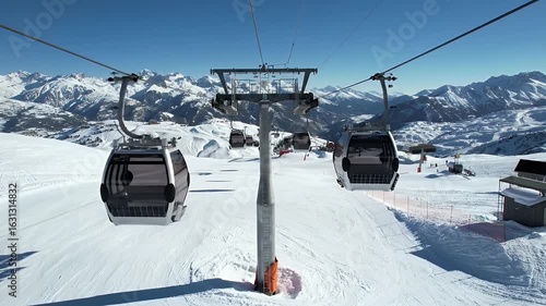 Riding a modern gondola ski lift up a snowy mountain range on a bright sunny day with panoramic views of the alpine landscape and ski slopes