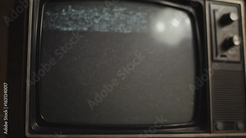 In a dark setting, a hand turns the dial on a vintage television. The screen flickers with static before settling on a solid green screen, perfect for chroma key compositing and nostalgic projects.