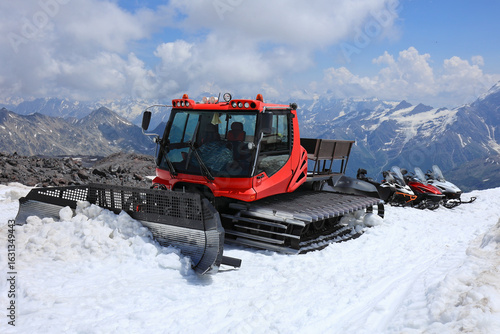 Bild auf Leinwand A Red Snowcat (Snow Groomer) And Snowmobiles Parked On A Glacier High In The Caucasus Mountains In Summer