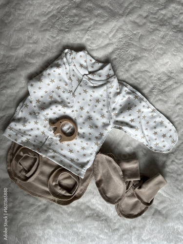 A turtleneck, diaper panties, socks, a wooden elephant teether. Cute pastel-colored clothes, accessories for newborns. Flatley, top view