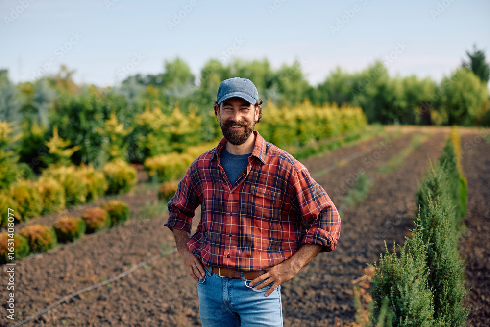Fototapeta premium Happy plant nursery owner in field looking at camera.