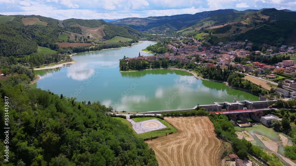 Drone view of Sassocorvaro village overlooking Mercatale dam, surrounded by forested hills in Italy Drone view of Sassocorvaro village overlooking Mercatale dam, surrounded by forested hills in Italy