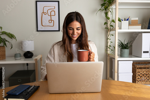 Tapeta Happy young woman working at home office having coffee