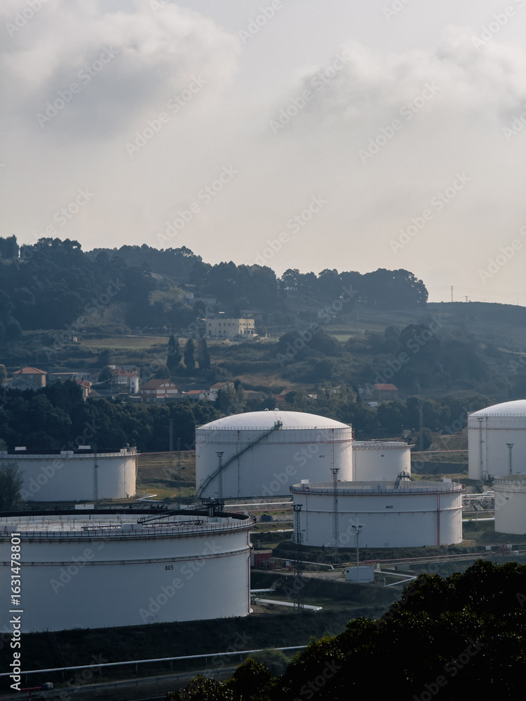 Fototapeta premium Large white oil storage tanks in rural industrial landscape