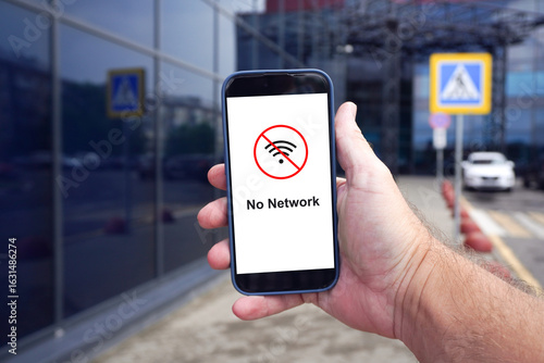 man holding smartphone showing no network symbol in airport parking lot