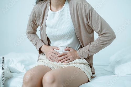 Bilde på lerret Women who are experiencing stomach pain in bed, stomach pain from food poisoning, stomach pain and digestive problems, gastritis or diarrhea, women who are menstruating