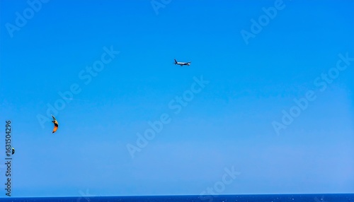 Clear sky, distant plane, kitesurfing