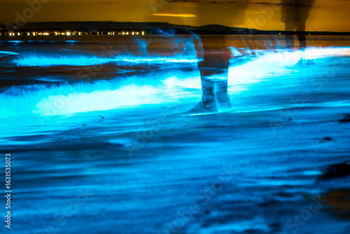 Bioluminescent waves shimmer along the shoreline in New South Wales, Australia, creating a surreal glow in the night.