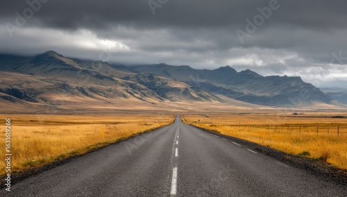 Empty road stretching into a mountainous landscape under a dramatic sky