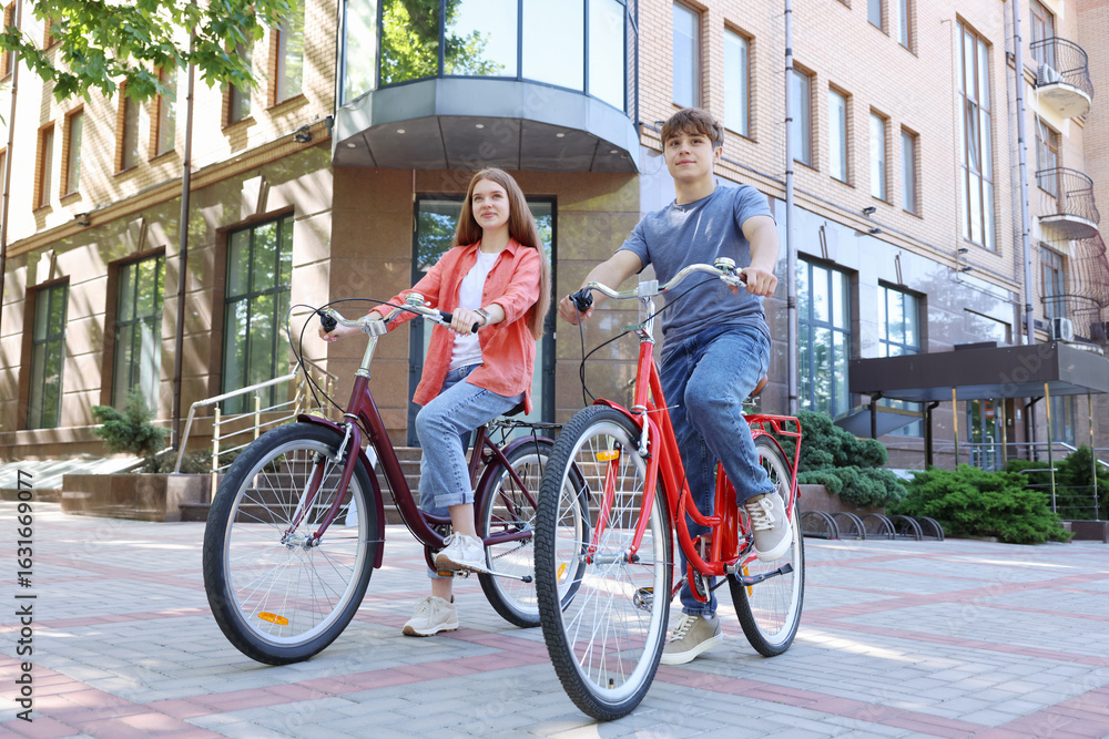 Obraz premium Teenage girl and boy riding bicycles on city street
