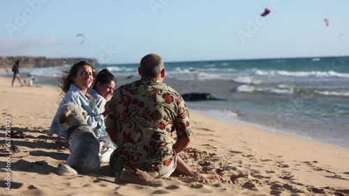 Friends enjoying beach with dog watching kitesurfers