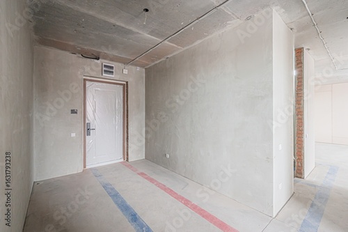 Wallpaper Mural An unfinished room with bare concrete walls and floor. A door, covered in plastic, is in the left. Visible wiring and exposed brick are present Torontodigital.ca