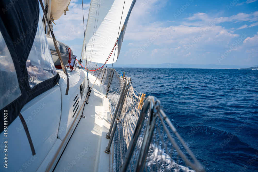 Fototapeta premium Side of a sailing yacht cutting through the sea with full sails near Croatia. Motion, freedom, sailing lifestyle and adventure on the open water.