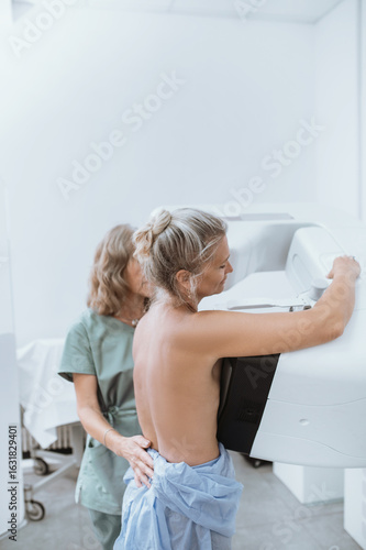  woman patient undergoes mammography procedure on mammograph digital mammography machine in modern clinic with doctor. Regular medical examination, screening for breast cancer
